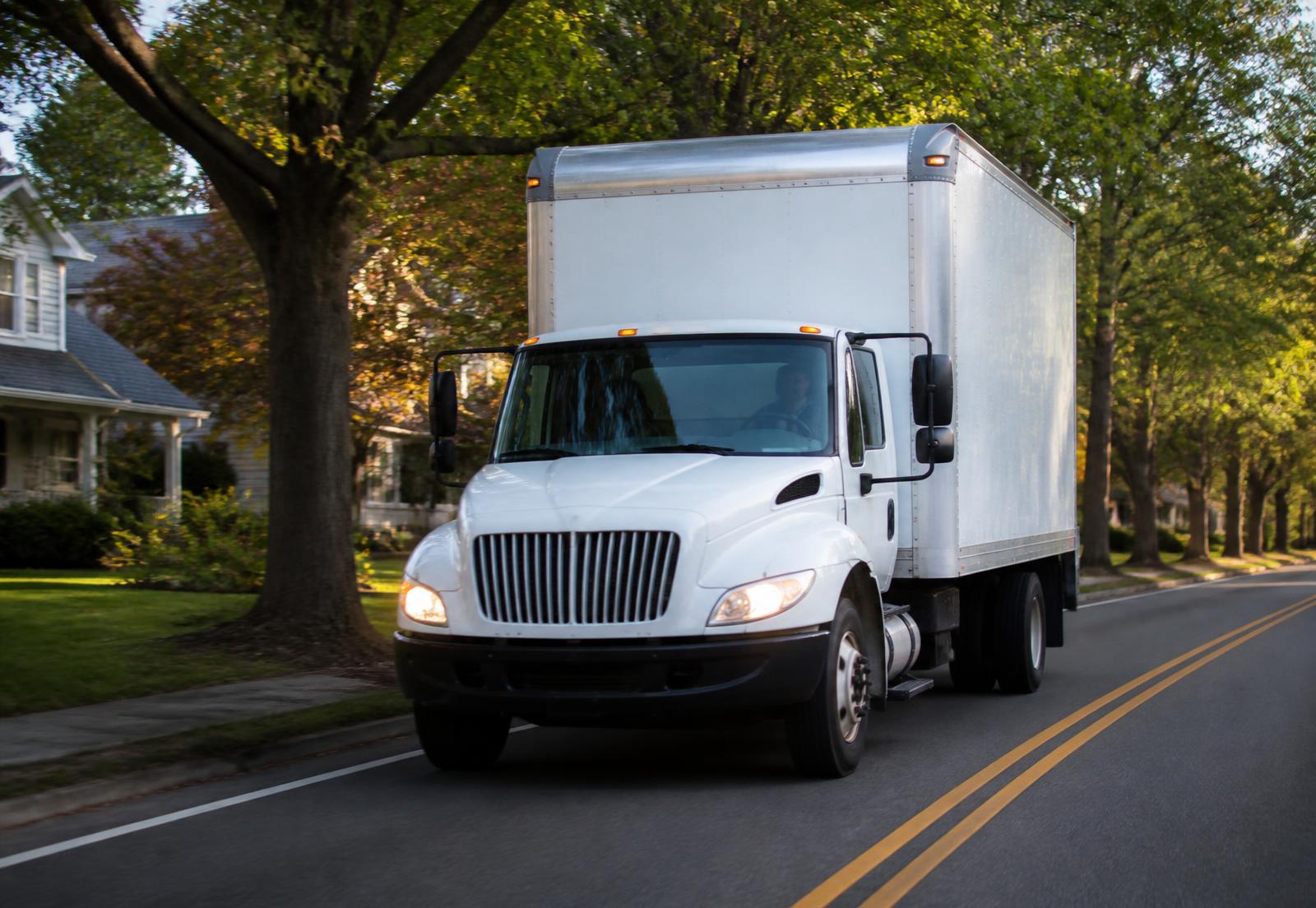 A residential moving truck traveling through a suburban neighborhood